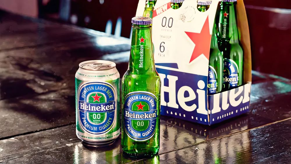 heineken0pourcent Pack de bières Heineken 0.0% avec une bouteille et une canette sur une table, et un pack de six en arrière-plan.