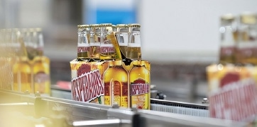nos_innovations_tuiles Bouteilles de bière Desperados alignées sur une chaîne de production dans une usine, prêtes pour l'emballage.